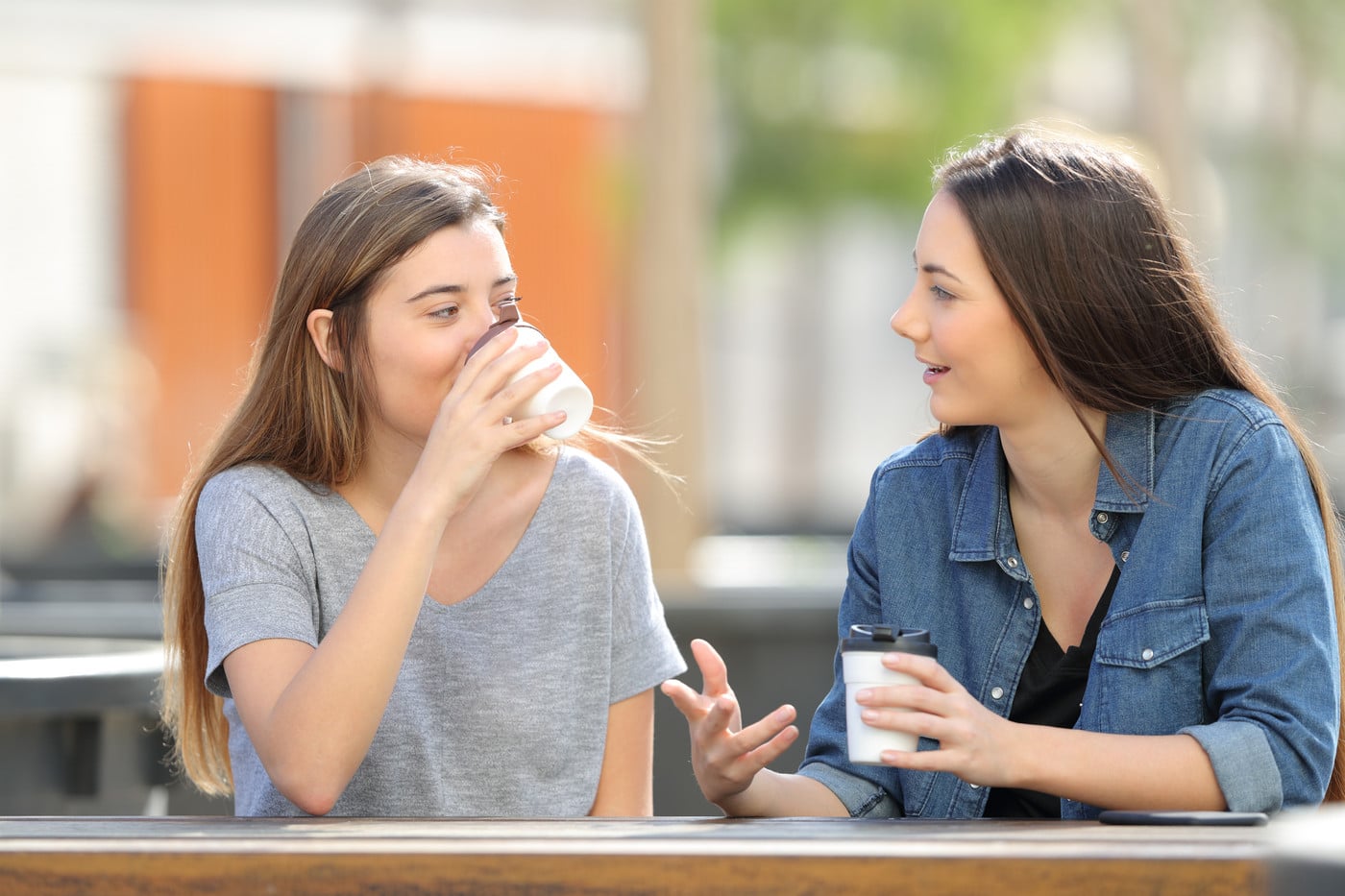 To unge kvinner drikker kaffe og prater sammen