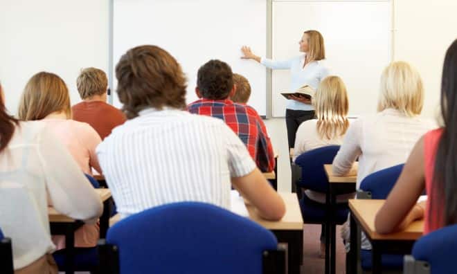 Ryggen på flere mennesker i en undervisningssituasjon med en kursleder foran i lokalet