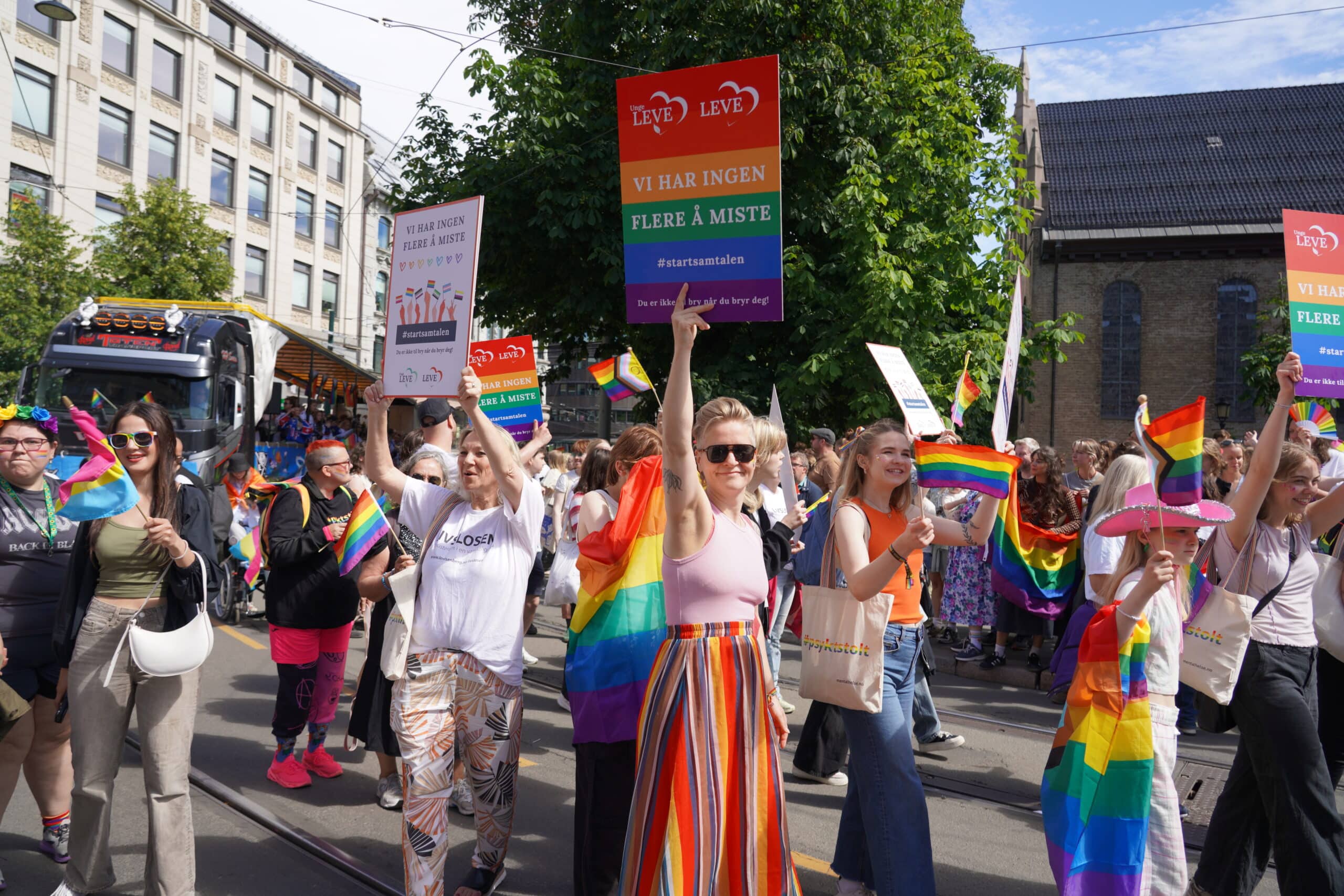 Mennesker går i pride-parade med skilt.