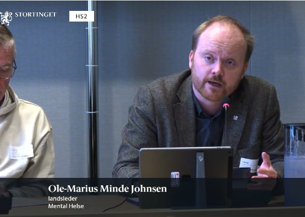 Mann snakker i mikrofon på Stortinget
